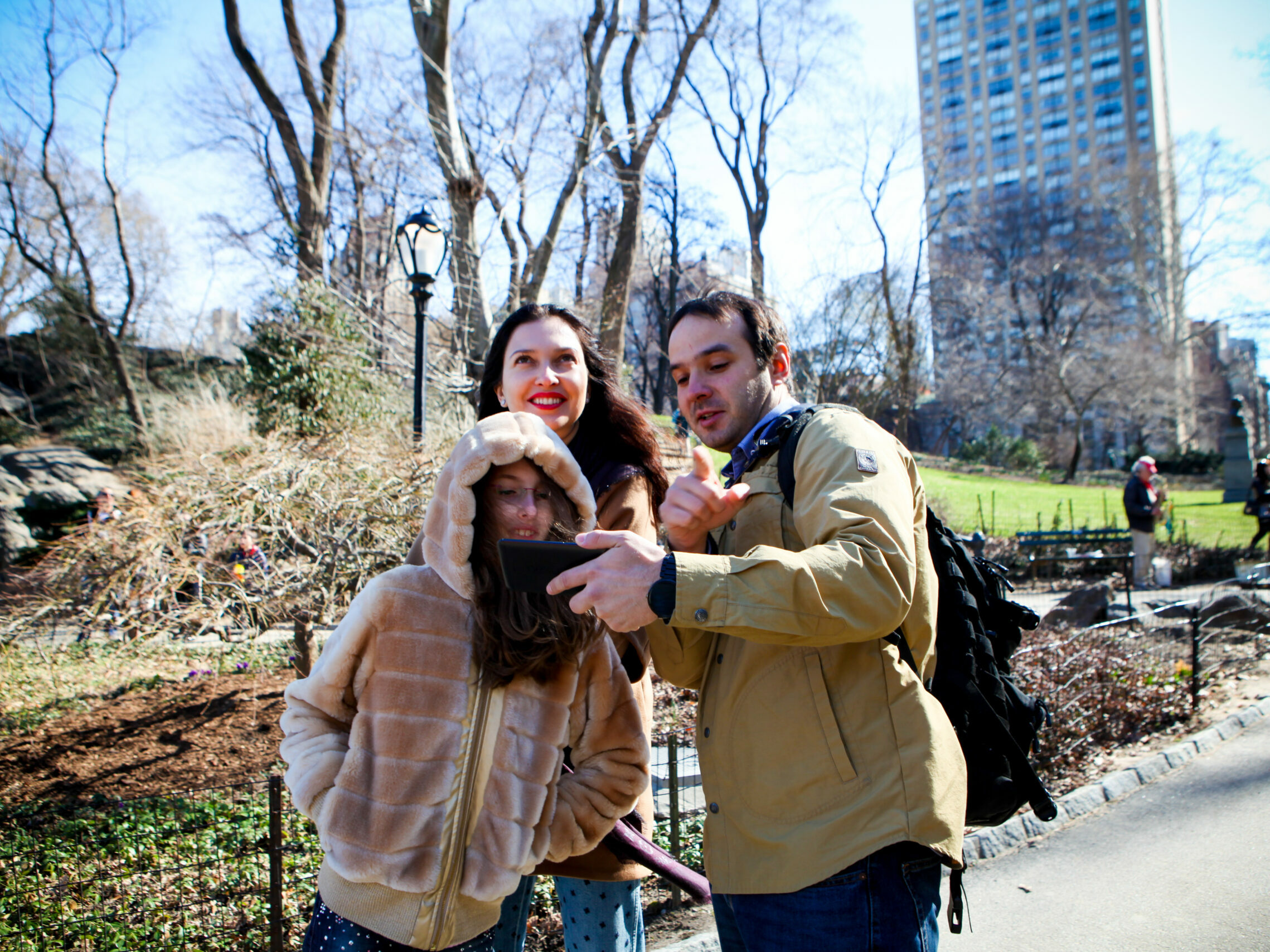 Slava shows something to two guests on a walking tour in early spring Central park