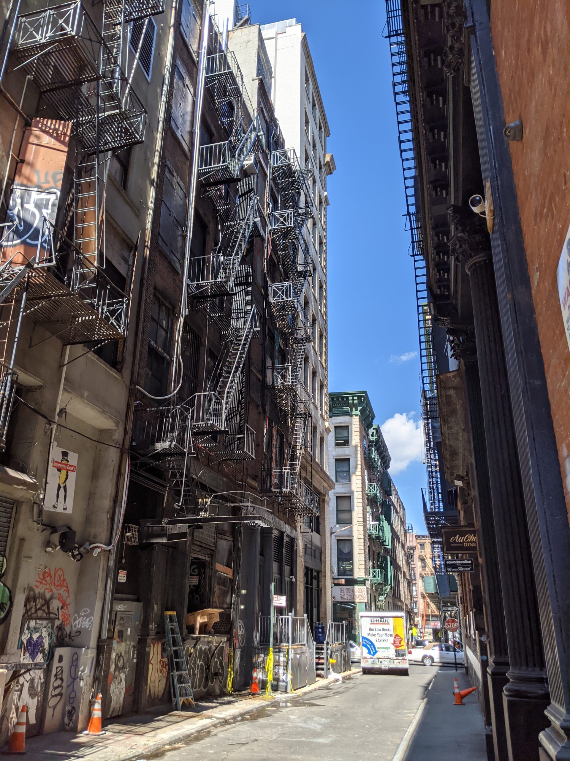 an alley with relative tall buildings and a lot of fire escapes