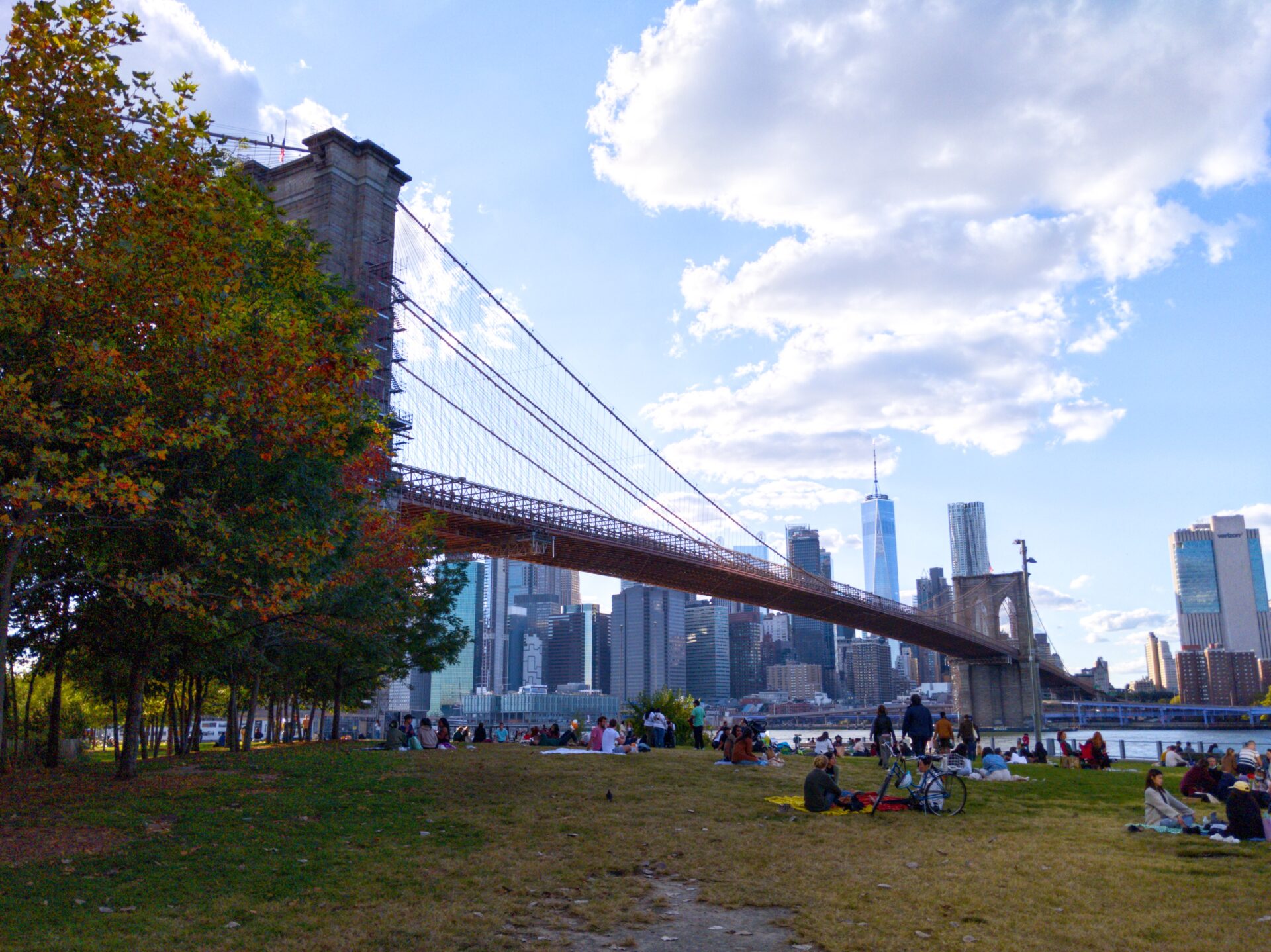 Brooklyn bridge goes to Financial District, people picnic on the Brooklyn side