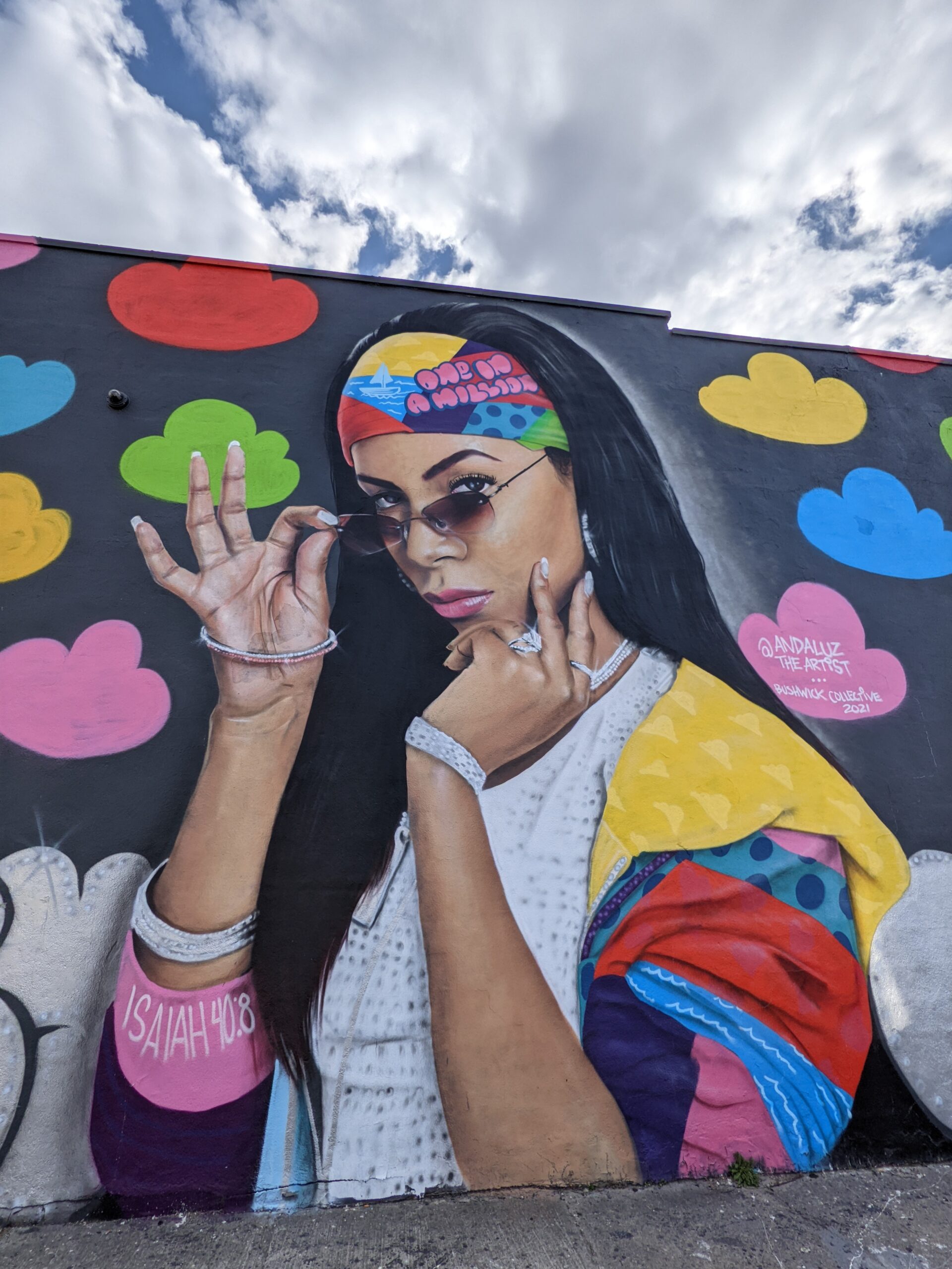 a mural of a brightly dressed woman in sunglasses, caption: isaiah 40:8