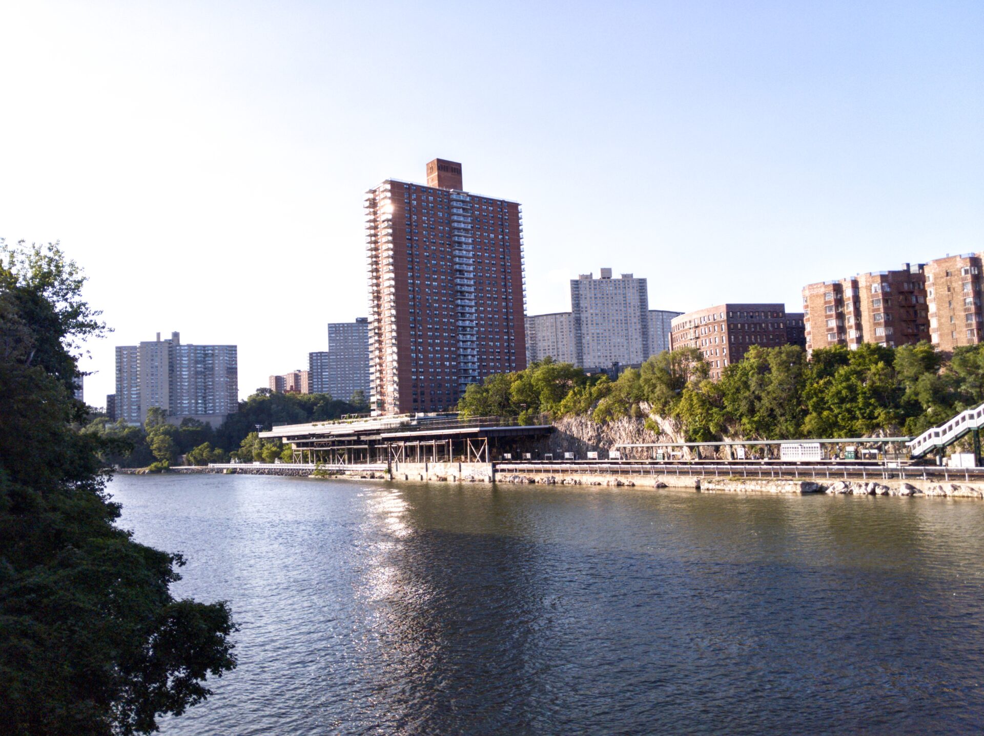 a river and a railroad station on the other side, under apartment buildings